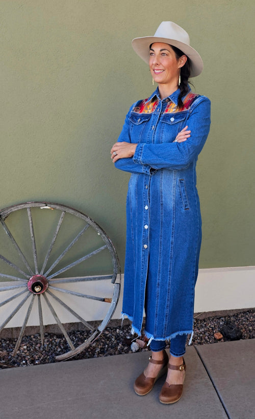 Full-length front view of a woman wearing the Pilot Rock denim duster with colorful wool shoulder panels.