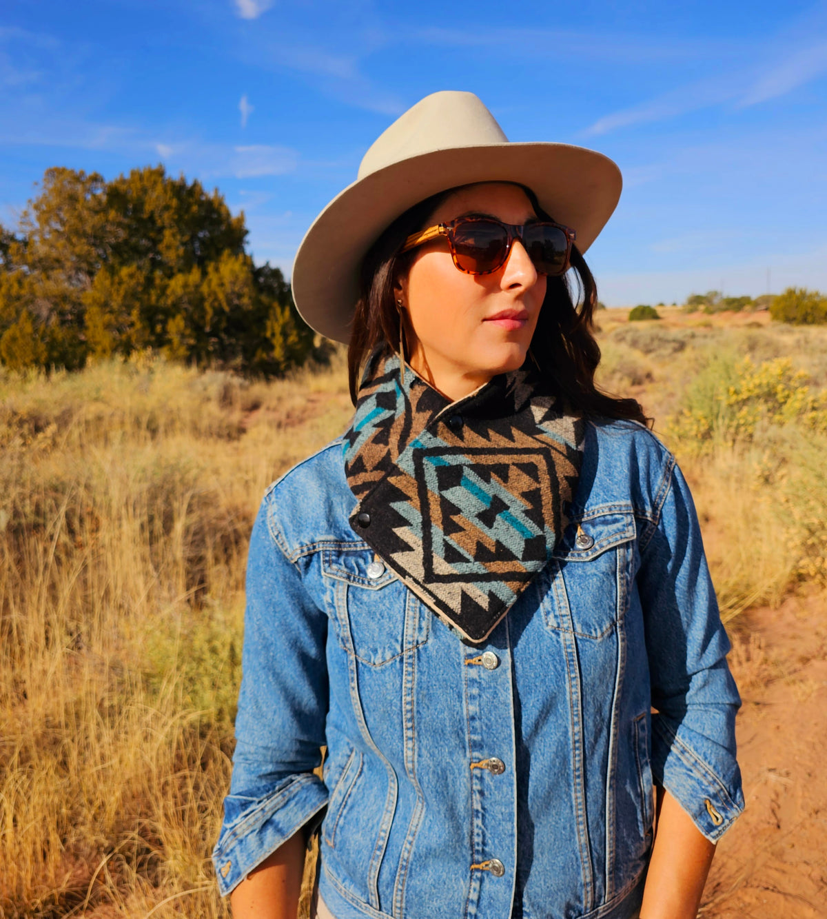 Woman wearing the Black/Tan geometric cowl with a denim jacket and wide-brimmed hat in a sunlit field.