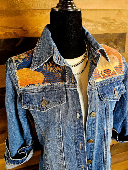 Close-up of the Land of the Buffalo denim duster’s buffalo-patterned wool shoulder panels and button-flap chest pockets.