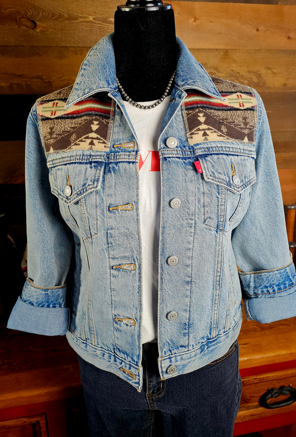Front of the Spirit of the People denim jacket on a mannequin, with patterned wool yokes and rolled sleeves.