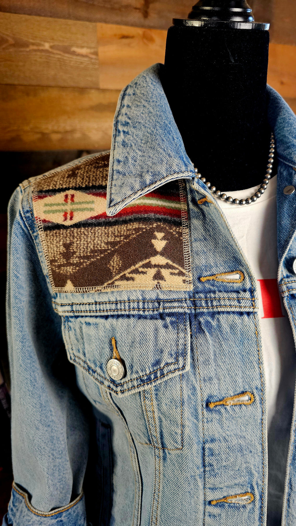 Angled close-up of the Spirit of the People wool shoulder patch, denim collar, and chest pocket.