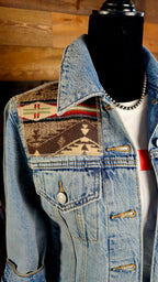 Angled close-up of the Spirit of the People wool shoulder patch, denim collar, and chest pocket.