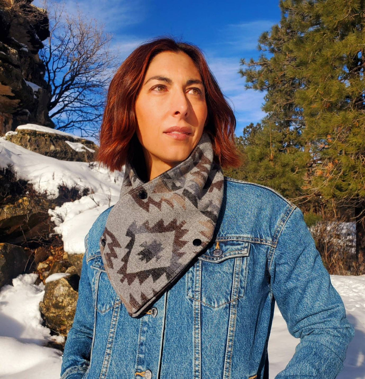 Woman wearing the gray and charcoal geometric Grey Aztec Western cowl over a denim jacket in a snowy landscape.