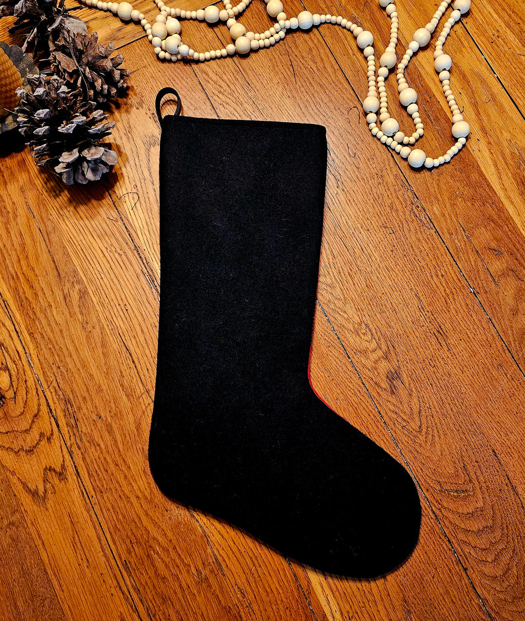 Plain black reverse of a Buffalo Check Christmas stocking laid flat on wood.