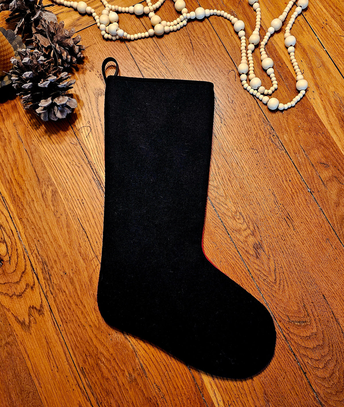 Plain black reverse of a Buffalo Check Christmas stocking laid flat on wood.