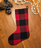 Front of a red and black buffalo check Christmas stocking displayed flat on a wooden surface.