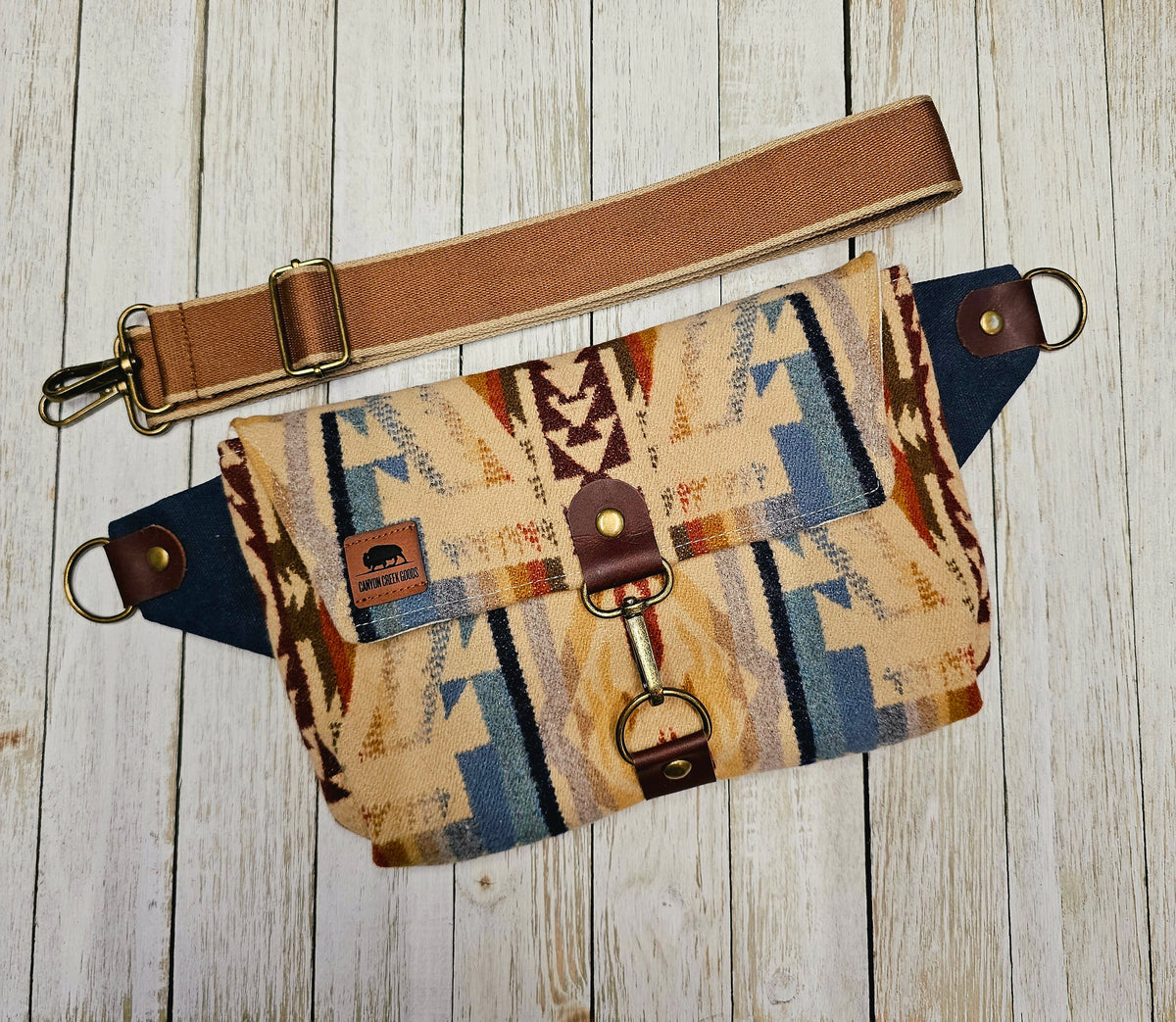 Shonto Wheatlands sling laid flat with a brown strap, geometric wool fabric and exterior zip pocket.