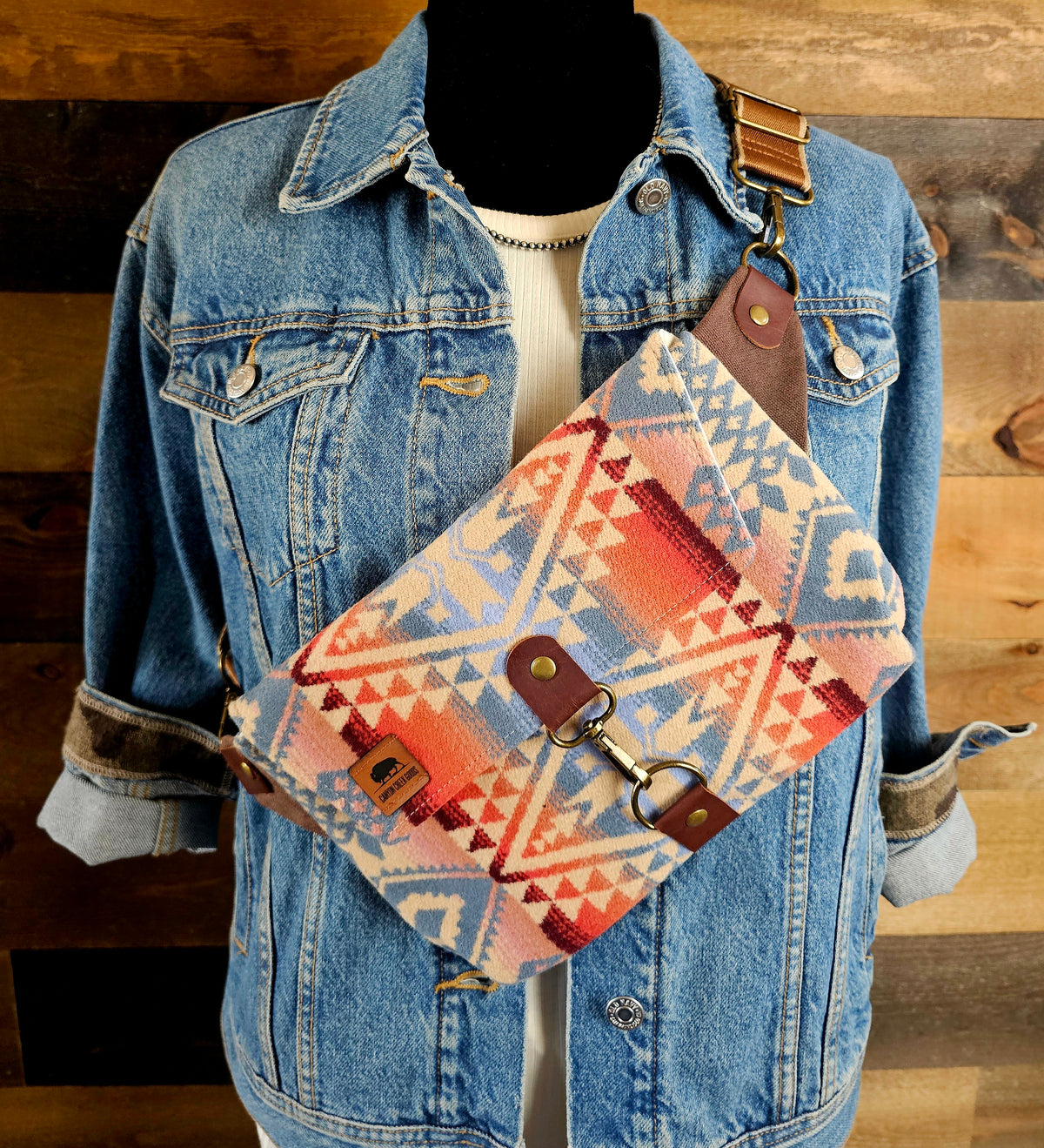 Canyonlands crossbody sling with red, blue and cream geometric fabric, worn over a denim jacket.
